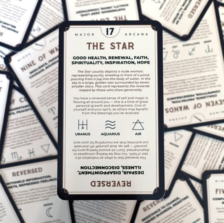 The Star tarot card rests against a scattered pile of tarot cards.