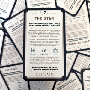 The Star tarot card rests against a scattered pile of tarot cards.